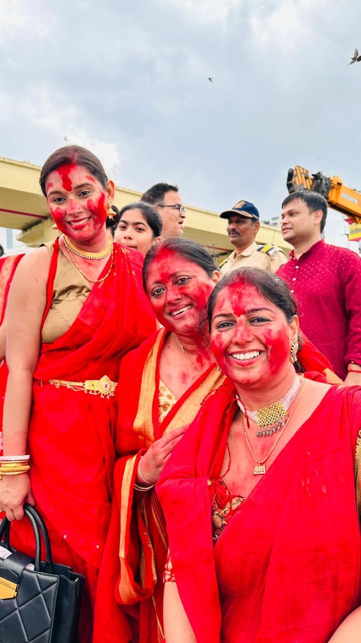 Three women smiling in red sarees with sindoor during Pujo 2025
